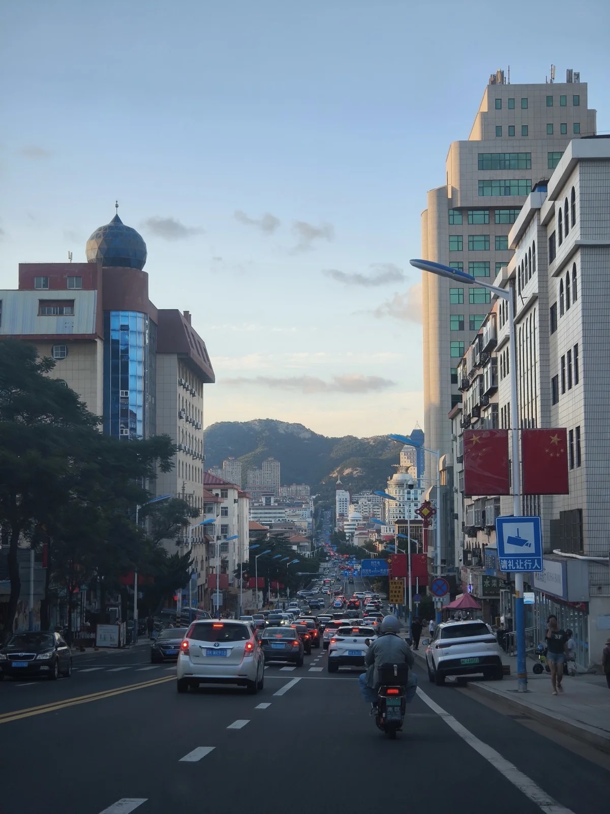 威海市区的主干道纵深向前,车流密集,道路尽头立着苍翠山峦
